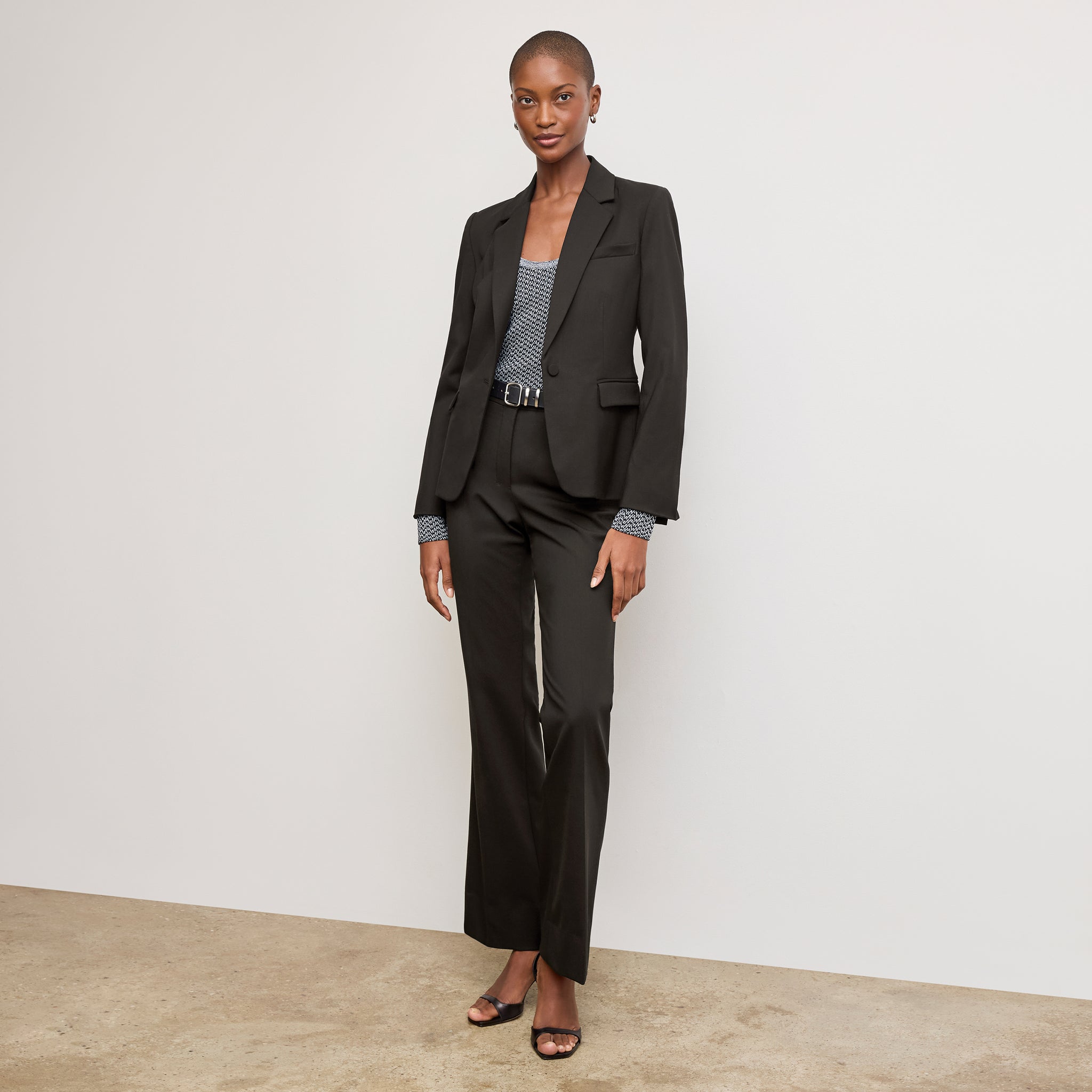Front image of a woman sitting wearing the Horton pant in black