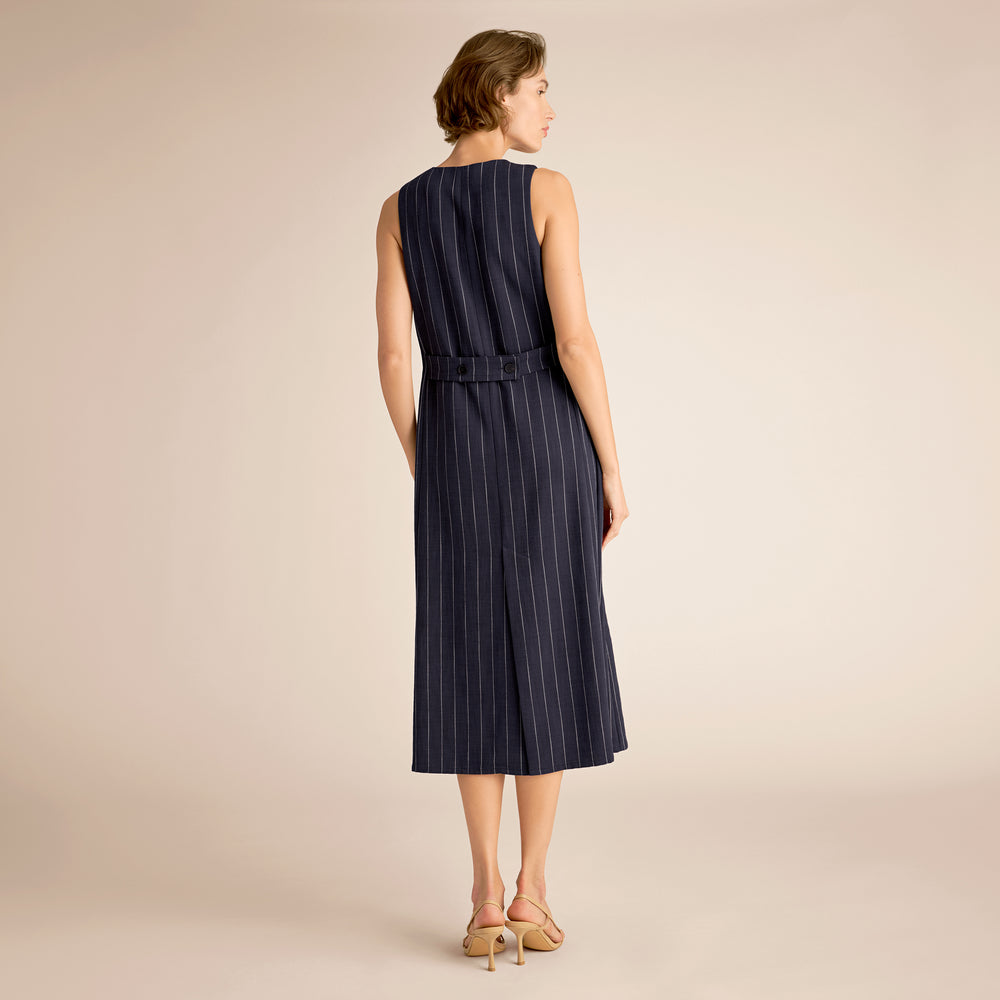 Woman wearing a navy pinstripe dress on a beige background
