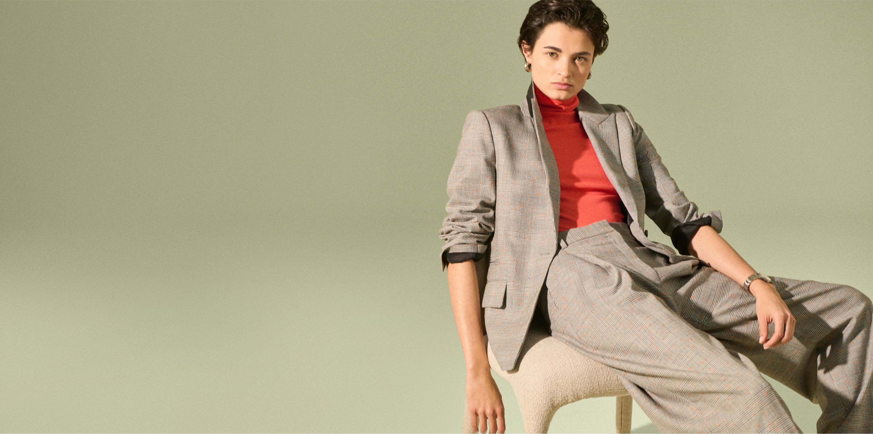Image of a woman wearing a gray suit with a coral turtleneck