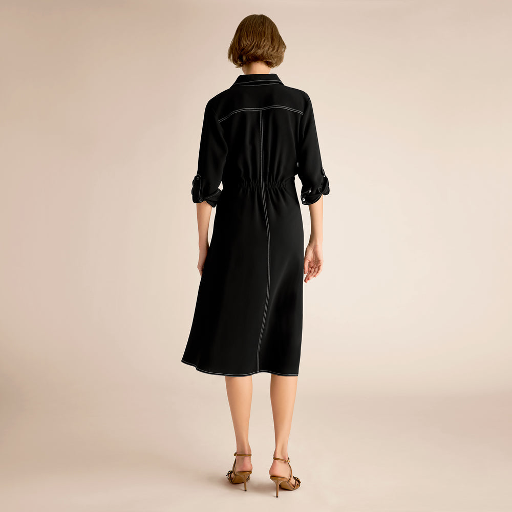 Woman wearing a black dress on a beige background