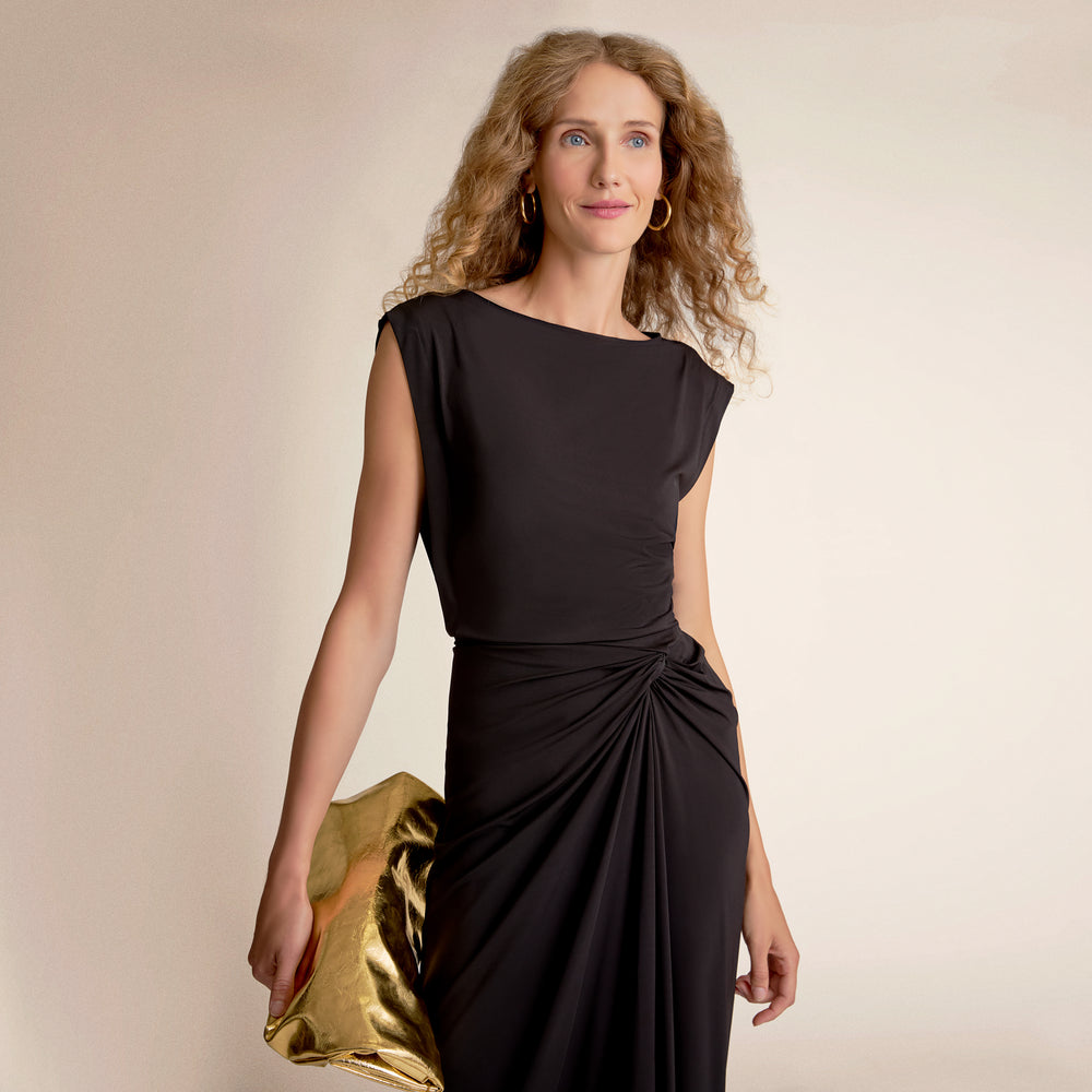 Woman wearing a black dress holding a gold clutch