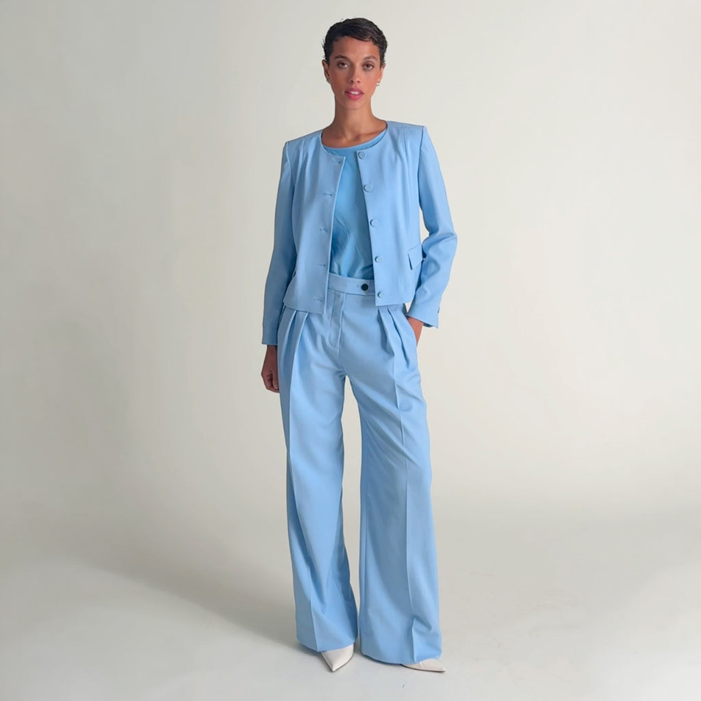 Woman wearing a light blue jacket and pant with a matching shirt