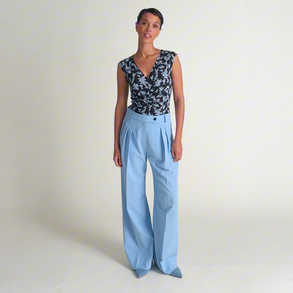 Video of a woman wearing a navy and light blue printed top with light blue pants 