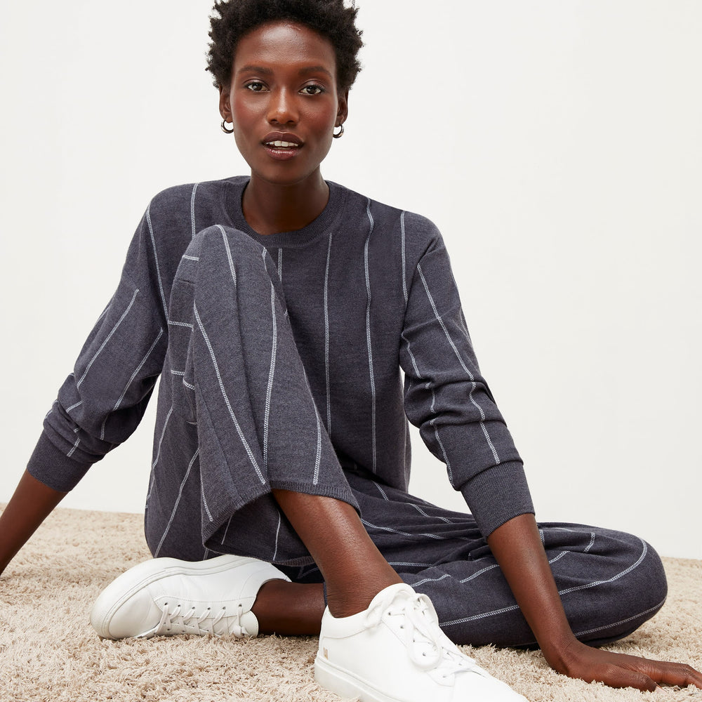 Front image of a woman standing wearing the Ingola Sweater—Braided Stripe in Charcoal / Ivory